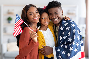 Proud veteran family wrapped in American flag, highlighting VA loan benefits for military families in NY & PA
